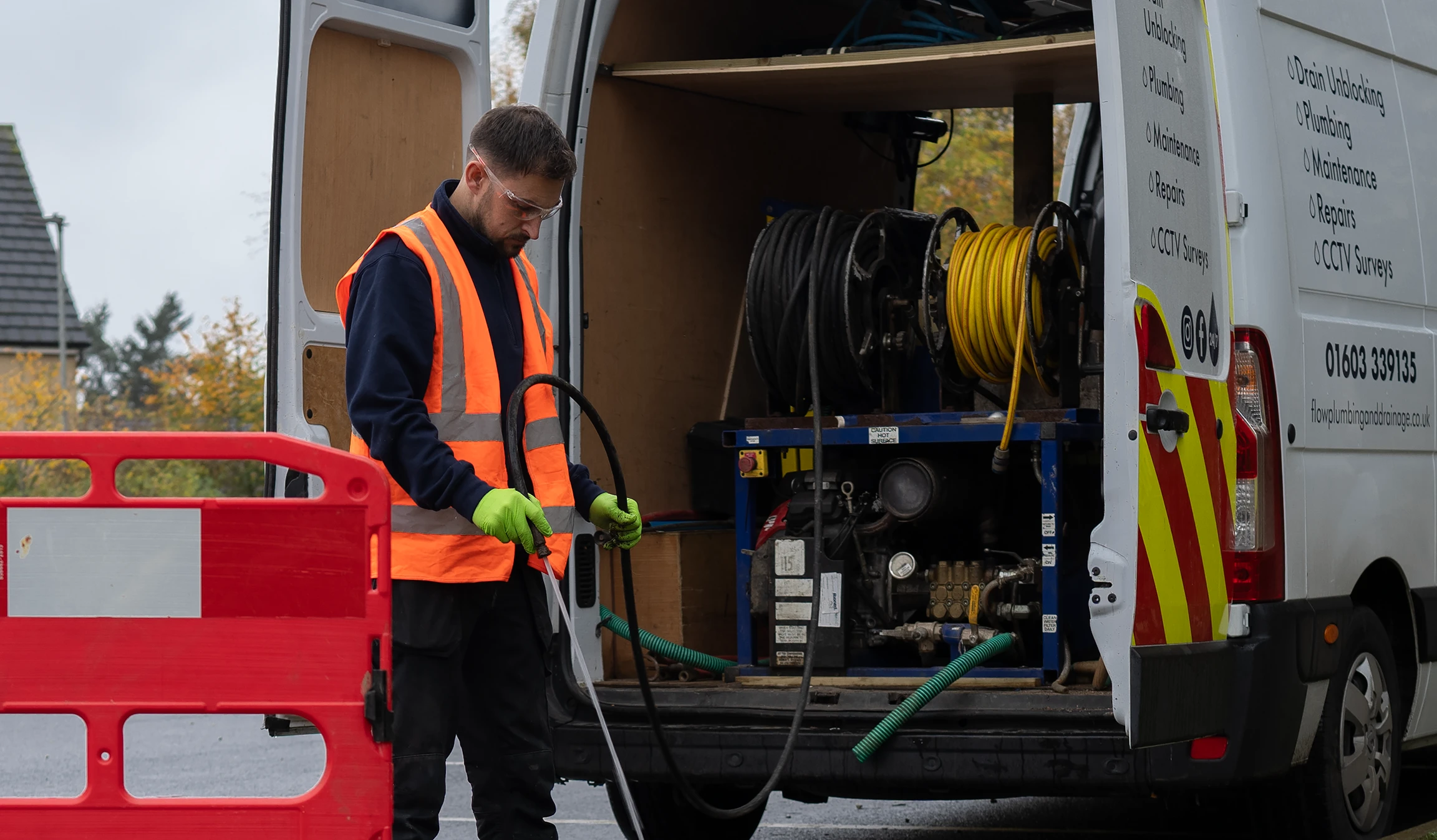 Flow Plumbing and Drainage engineer unblocking a drain using the equipment from the back of his van